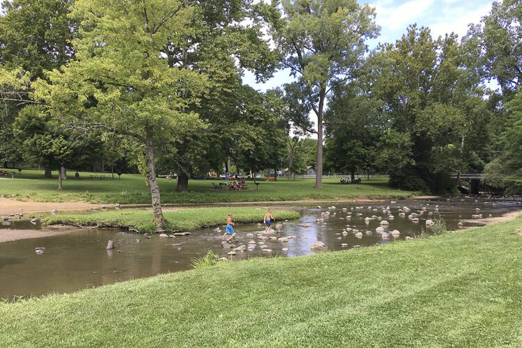 <span class="content-image-text">Kids frolic in the wading area near the Hinckley Lake swimming beach as picnickers lounge in the background.</span>