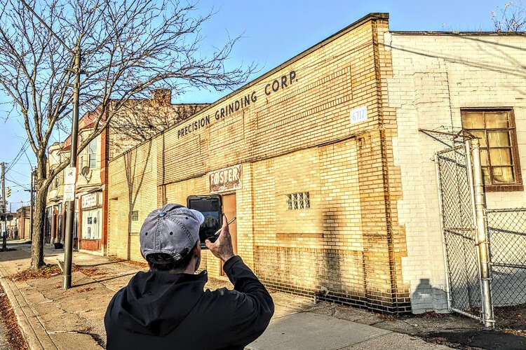 Adrian Marti of the Western Reserve Land Conservancy photographs a building on St. Clair Avenue for an inventory of Cleveland properties.