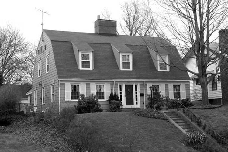 1467 Lewis Drive, built in 1919, the house features a steeply pitched gambrel roof that contains a second story, a massive chimney in the center of the roof, and three dormers with shed roofs each in the front and rear