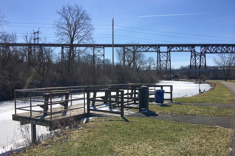 A fishing platform overlooks the canal as the CSX Short Line rail bridge is visible in the background.