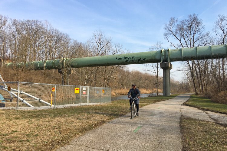 A cyclist rolls over the trail and under the Southwest Interceptor.
