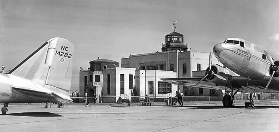 <span class="content-image-text">Administration Building at the airport with the tail of plane NC14282, an American Airlines DC-2, to the left, and the nose of an American Airlines DC-3 is on the right (</span>