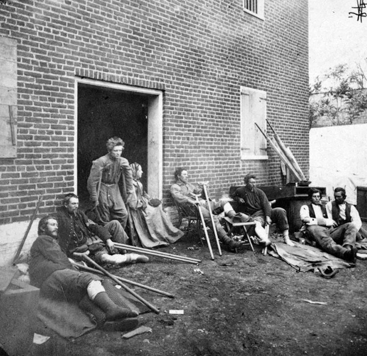 <span class="content-image-text">Soldiers, wounded in the Battle of the Wilderness, resting outside a building in Fredericksburg, Virginia, May 20, 1864</span>