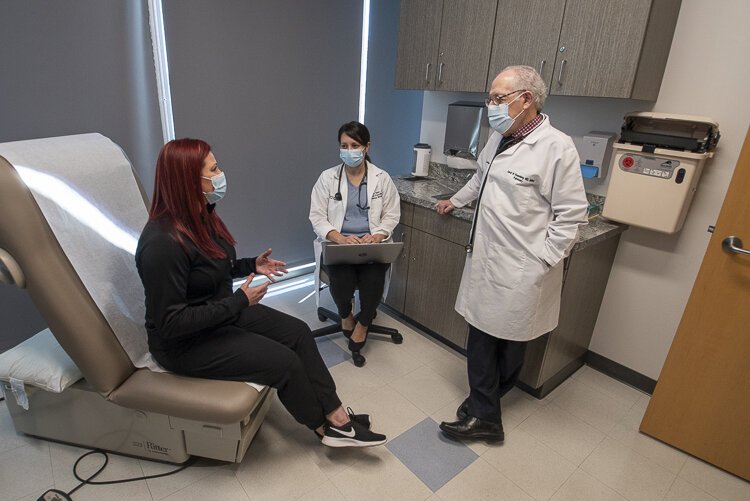University Hospitals COVID Recovery Clinic medical director David Rosenberg, far right, and internal medicine nurse practitioner Juliane Torer  talk with a Long Covid patient.