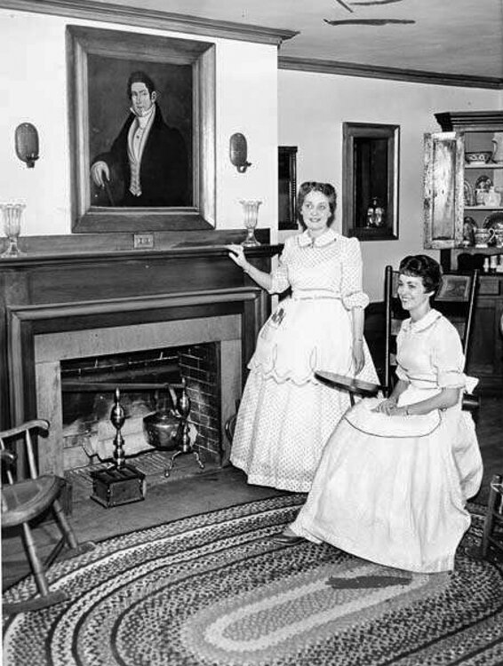 <span class="content-image-text">Women in costume pose at the fireplace in the Dunham Tavern Museum 1960</span>