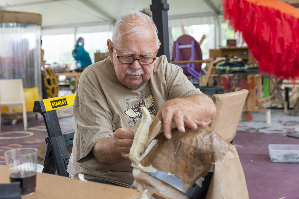 Chuck Supinski working on a float piece for the Parade in the artist tent