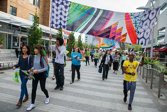 <span class="content-image-text">A group of students marched holding fabric banners from Praxis Fiber Workshop, Jessica Pinsky’s non-profit fiber arts center</span>