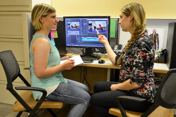 <span class="content-image-text">Erika Woodrum, FES Center Staff (CIA Biomedical Art 2014), works with Jeanette Coker (CIA student) editing video highlighting an FES Center research program</span>