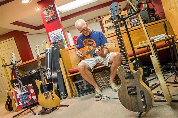 David Lackey playing one of his guitars at his home