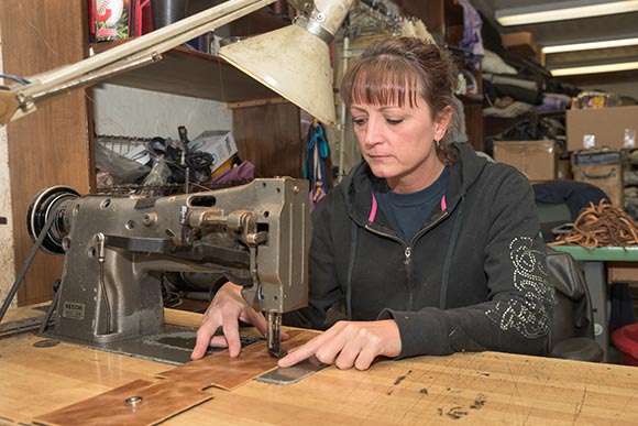Chuck's daughter Lori at the sewing maching at TRD Leather