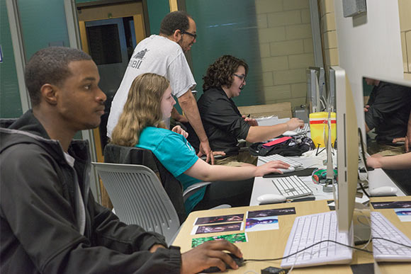 <span class="content-image-text">Instructor Robert Banks works with photography students in the NewBridge after School program</span>