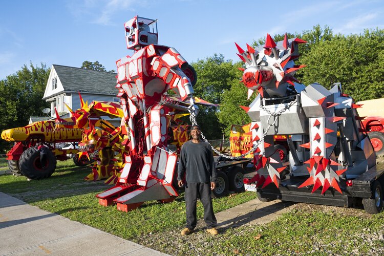 Red and yellow monster trucks and silver robots tower over the lot of automotive innovator Tim Willis.