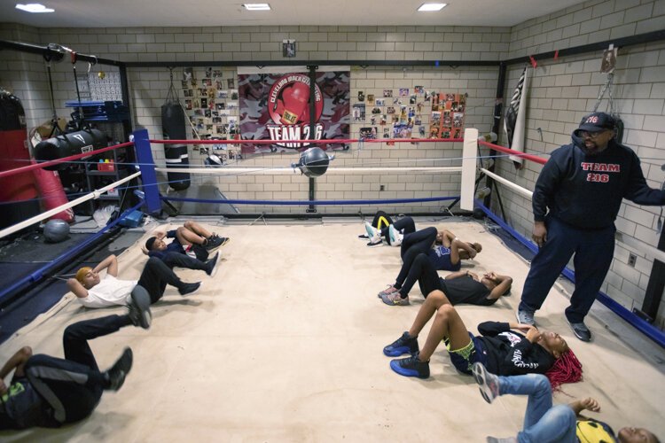 Boxers warm up with yoga and breathing exercises before moving along to boxing instruction.