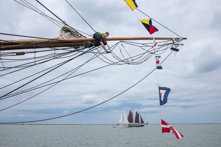 <span class="content-image-text">A shipmate precariously works on the rigging on The Flagship Niagara</span>