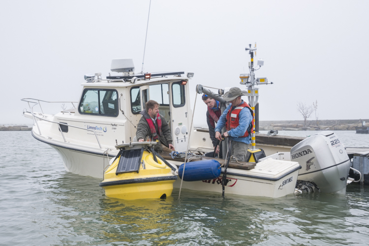 LimnoTech Project Engineer Ed Verhamme, engineer Brandon Ellefson and scientist Greg Cutrell prepare the buoy to be taken out to it's permanent location on the lake