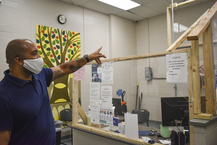 <span class="content-image-text">David Blunt, shows how the shelter has set-up a plexiglass barrier at its entryway to protect residents and staff during the pandemic.</span>