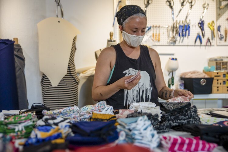 Valerie Mayen, owner of Yellowcake Shop, organizes an order of face masks inside her store in 78th Street Studios.