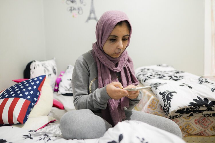 Israa Alhashal uses a mobile application to continue learning English despite her school closing.