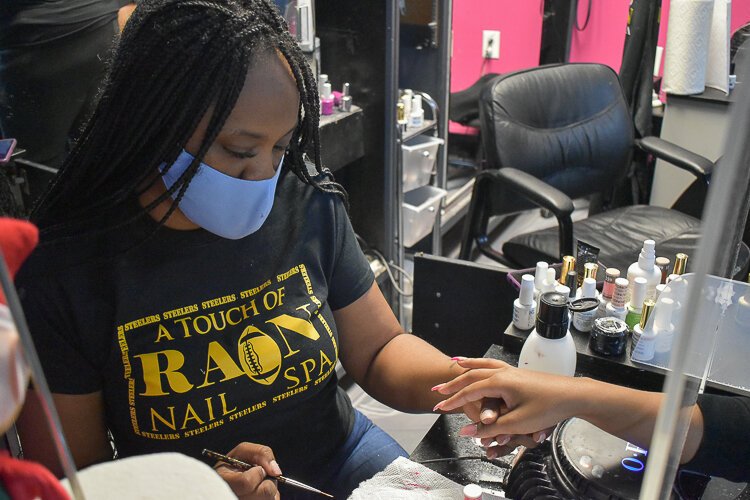 <span class="content-image-text">Rain Burnside, owner of A Touch of Rain Nail Spa in Larchmere, provides a manicure to a client during a November event meant to educate people on the Child Tax Credit.</span>