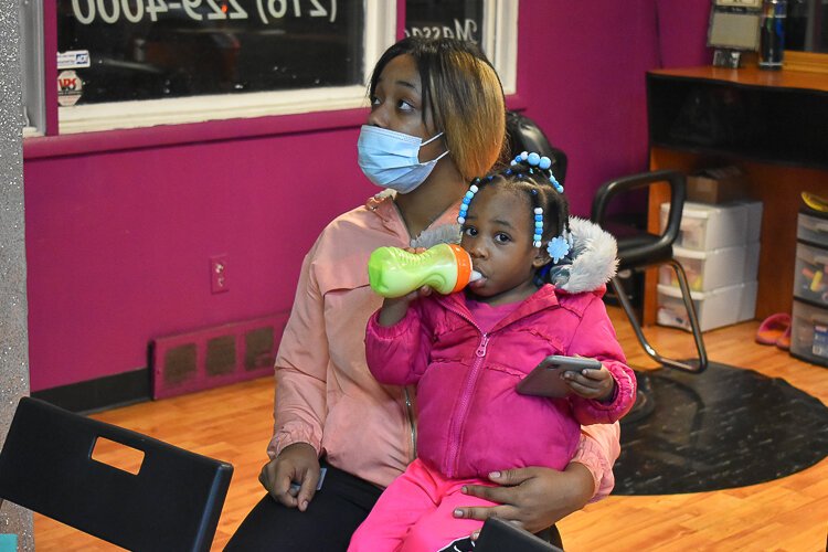 <span class="content-image-text">Kayla Minor, a local home health aide, sits with her two-year-old daughter A’Riyah as she learns about the Child Tax Credit during a November event at A Touch of Rain Nail Spa in Larchmere.</span>