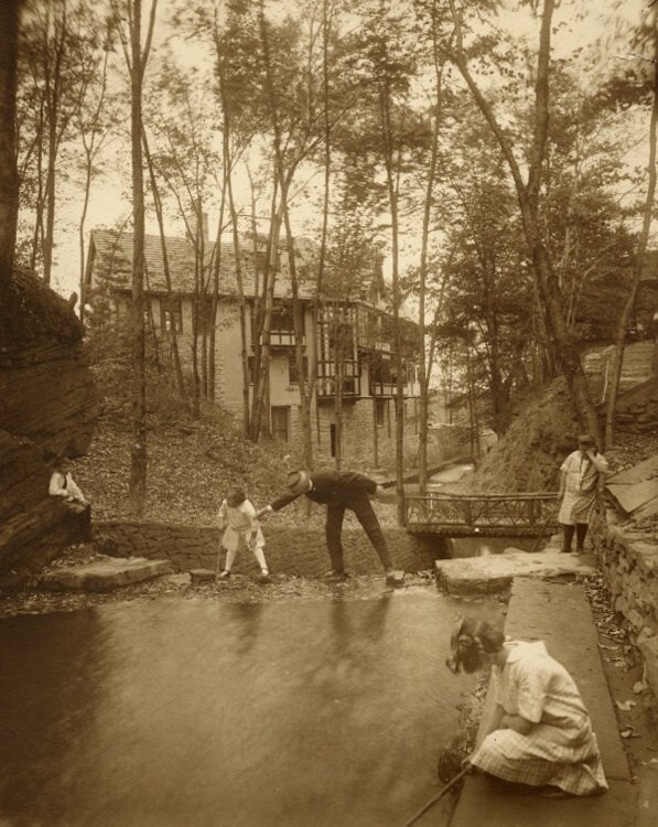 <span class="content-image-text">A man believed to be Barton R. Deming plays with his nieces in the creek behind the Deming house in 1917</span>