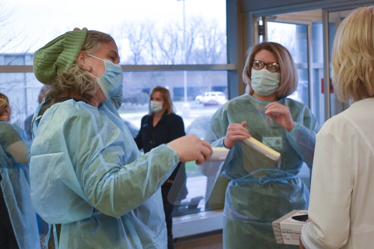 Dana Beattie, nurse with VNA Ohio, speaks with Tara Brown, clinical manager with VNA Ohio, as they prepare to put PPE gear on.
