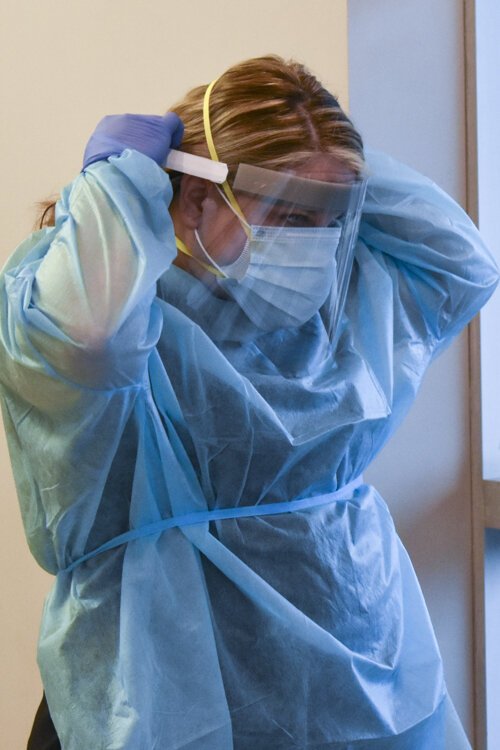 <span class="content-image-text">Nicole McGivern, a clinical manager puts on her PPE gear.</span>