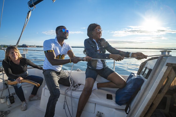First mate Cindy Bills watches as Charlotte and Emmanuel hoist the sail.
