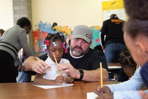 <span class="content-image-text">An Amazon associate helps a first grader girl at Andrew J Rickoff School complete a breakfast themed trivia challenge</span>