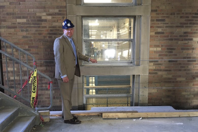 Pat Higley stands between old construction and new construction on the EHS site.