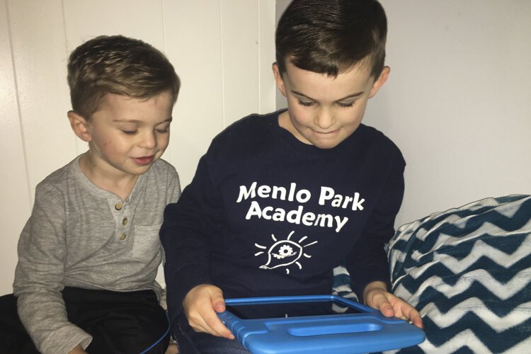 Kindergartner Weston Cobb and his little brother Elliot watched Menlo art teacher John Cycyk read “Little Red” by Bethan Woollvin.