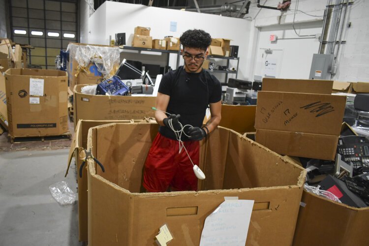 <span class="content-image-text">Jovanti Ramirez, a student at CMSD who has a summer internship with PCs for People, works to sort mice and other devices out of a bin in their warehouse.</span>