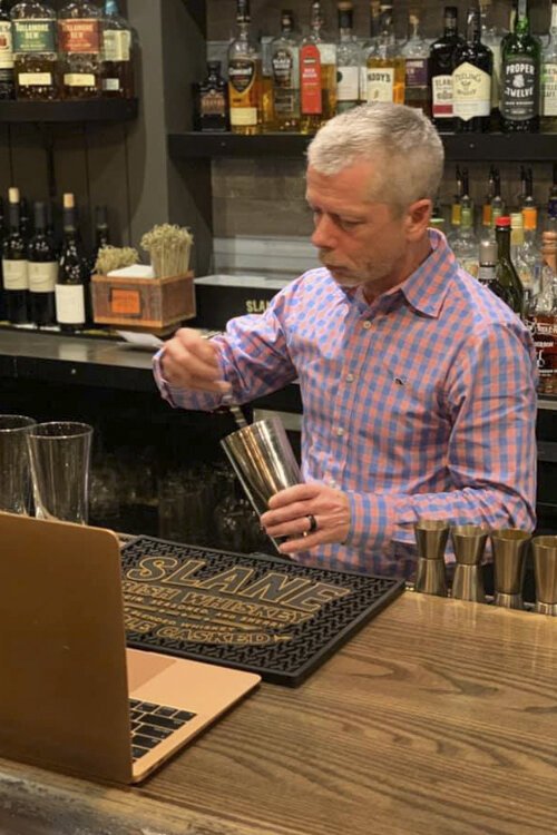 Declan Synnott, owner/operator at Parnell's Pub, behind the bar and in front of a laptop for a zoom cocktail class.