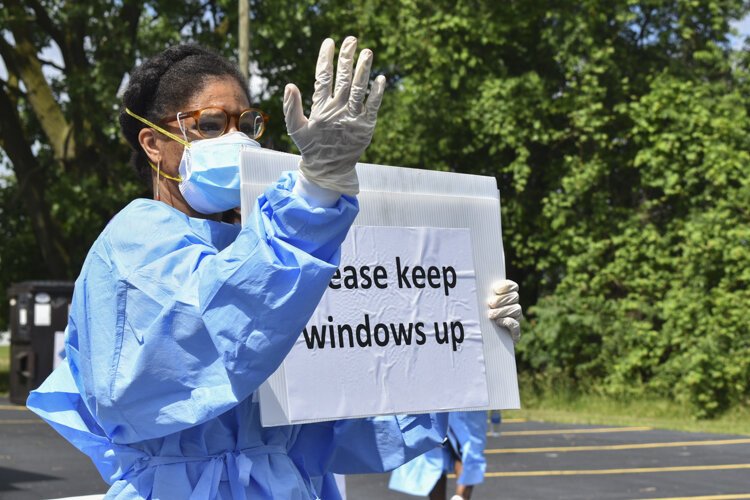 Kellee Williams, a community outreach liaison with the Cuyahoga County Board of Health, directs people through the lanes of a pop-up testing site in the parking lot of the Word Church on Kinsman Road in Cleveland back in early June.