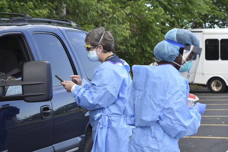 <span class="content-image-text">Dr. Heidi Gullett, left, Cuyahoga County Board of Health’s medical director, explains the process to a driver who came through a pop-up COVID-19 testing site at the Word Church on Kinsman Road in Cleveland back in early June.</span>