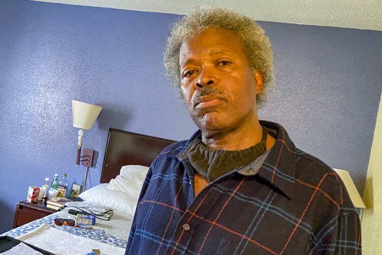 Abel Currie, 63, sits in his hotel room in May quarantined safely as he searches for a permanent apartment.