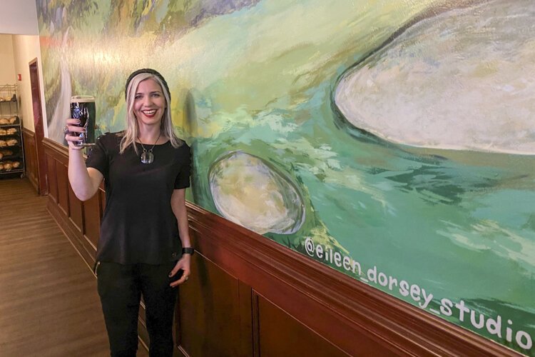 Artist Eileen Dorsey toasts the finish of her new mural at Flannery's Pub