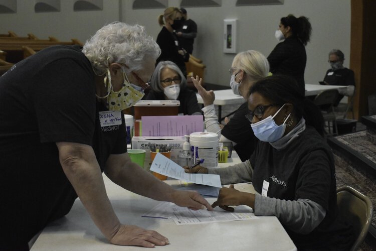 Employees and volunteers with Cleveland nonprofit Medworks get things in order before a vaccine clinic begins at Affinity Missionary Baptist Church in Cleveland’s Lee-Miles neighborhood.