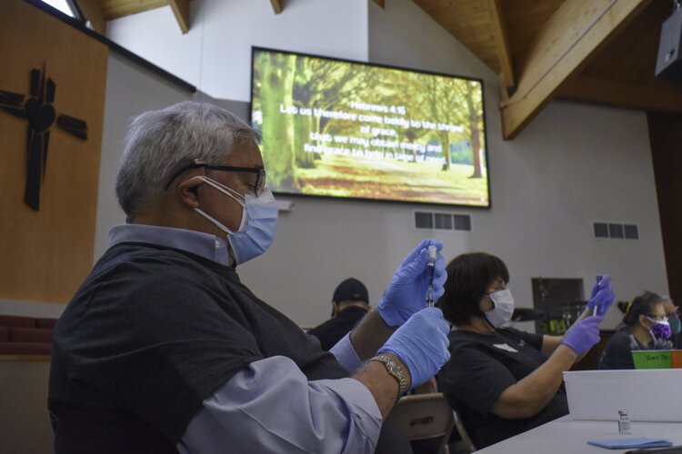 Several volunteers with Cleveland nonprofit Medworks prep vaccine doses at Affinity Missionary Baptist Church during a recent vaccine clinic.