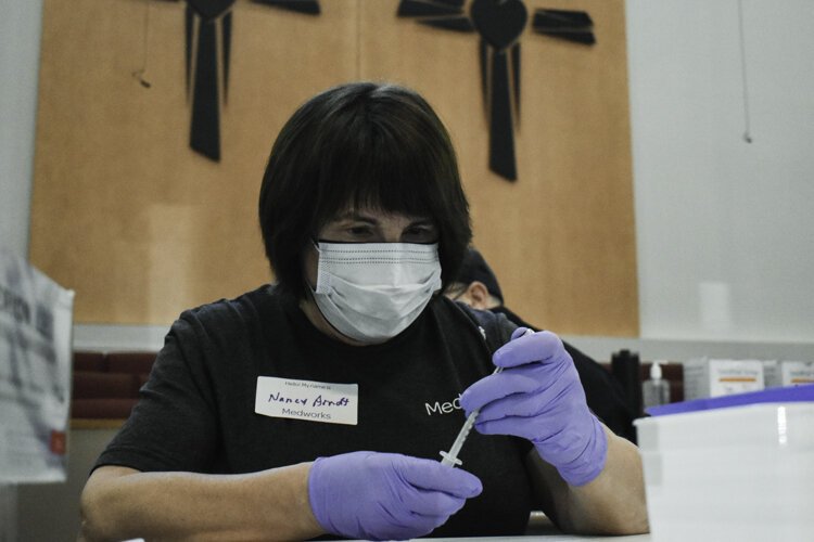 A volunteer with Cleveland nonprofit Medworks prep vaccine doses at Affinity Missionary Baptist Church during a recent vaccine clinic.
