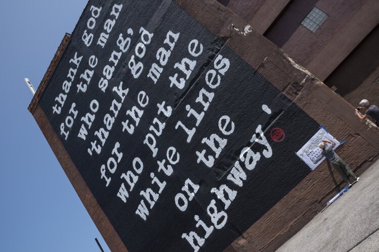 Cleveland native and Los Angeles-based street artist WRDSMTH putting his signature on the “Lover” Micheal Stanley tribute mural on Payne Ave.