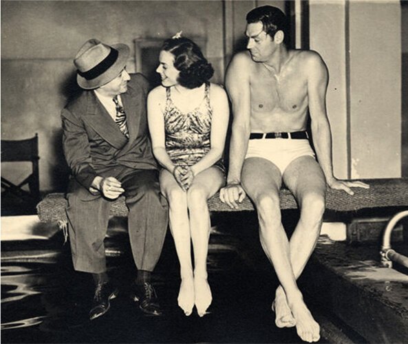 <span class="content-image-text">Billy Rose with Olympic swimmers Eleanor Holm and Johnny Weissmuller on a diving board at Billy Rose's Aquacade at the Great Lakes Exposition	</span>