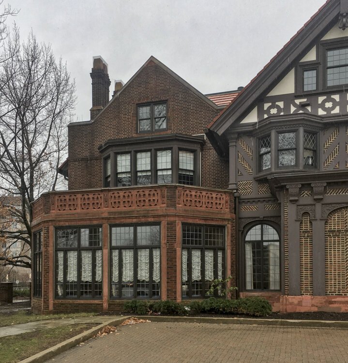 <span class="content-image-text">On the exterior, The Drury house boasts a red brick façade with recessed arches, bay windows, orange slate roof, dark chimney, and a brick tower.</span>