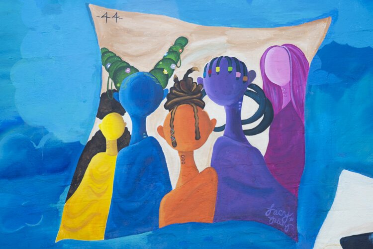 Storytime (BLM)” depicts a young Black boy under a tree, reading a story about his ethnicity and his family. The artists are Lacy “Lacerrrr” Talley, Michelle Suells, Aldonte Flonnoy, and Niquo Braxton.