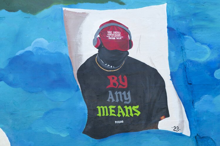 Storytime (BLM)” depicts a young Black boy under a tree, reading a story about his ethnicity and his family. The artists are Lacy “Lacerrrr” Talley, Michelle Suells, Aldonte Flonnoy, and Niquo Braxton.